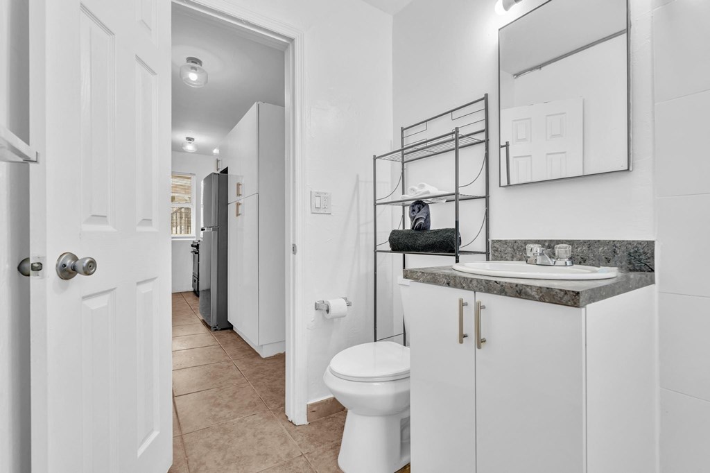 A bathroom with a toilet, sink, and mirror.