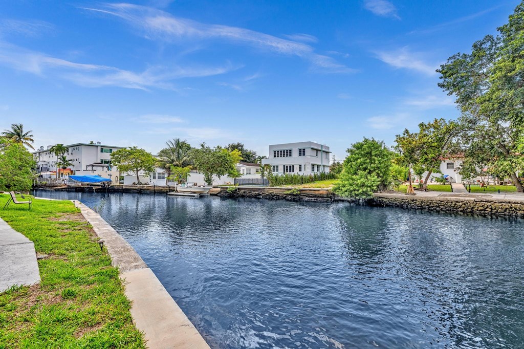 A serene waterfront scene with a clear blue sky and calm water.