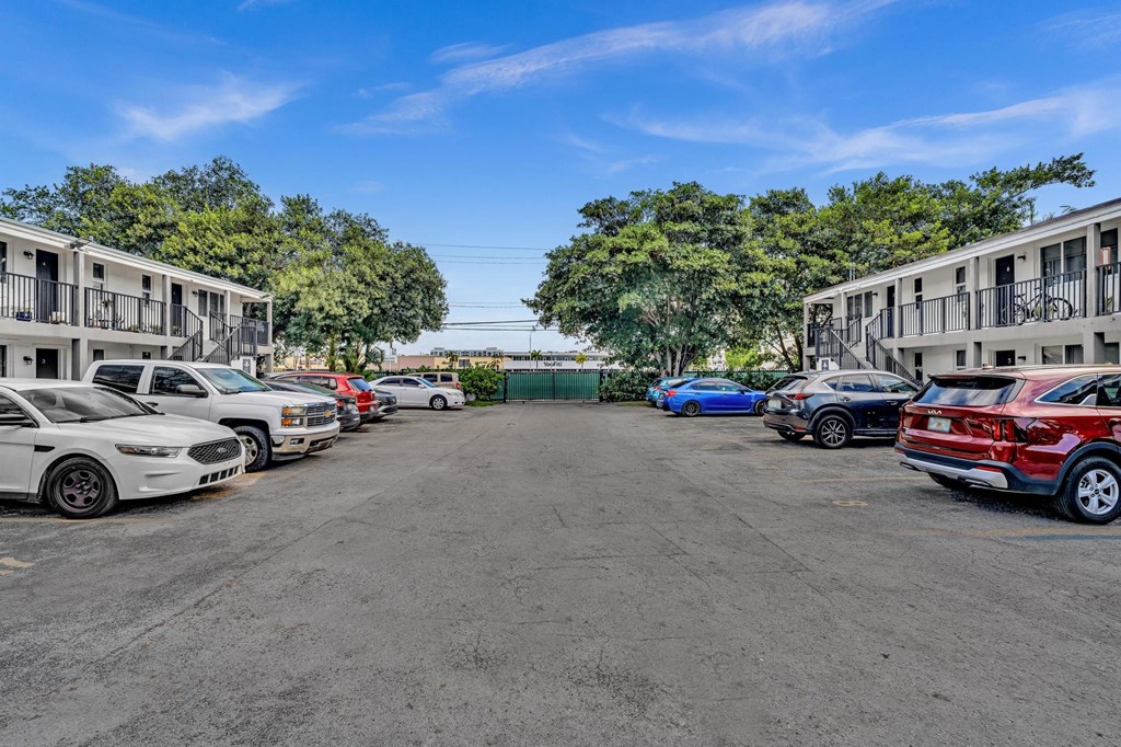A parking lot with several cars parked in front of apartment buildings.