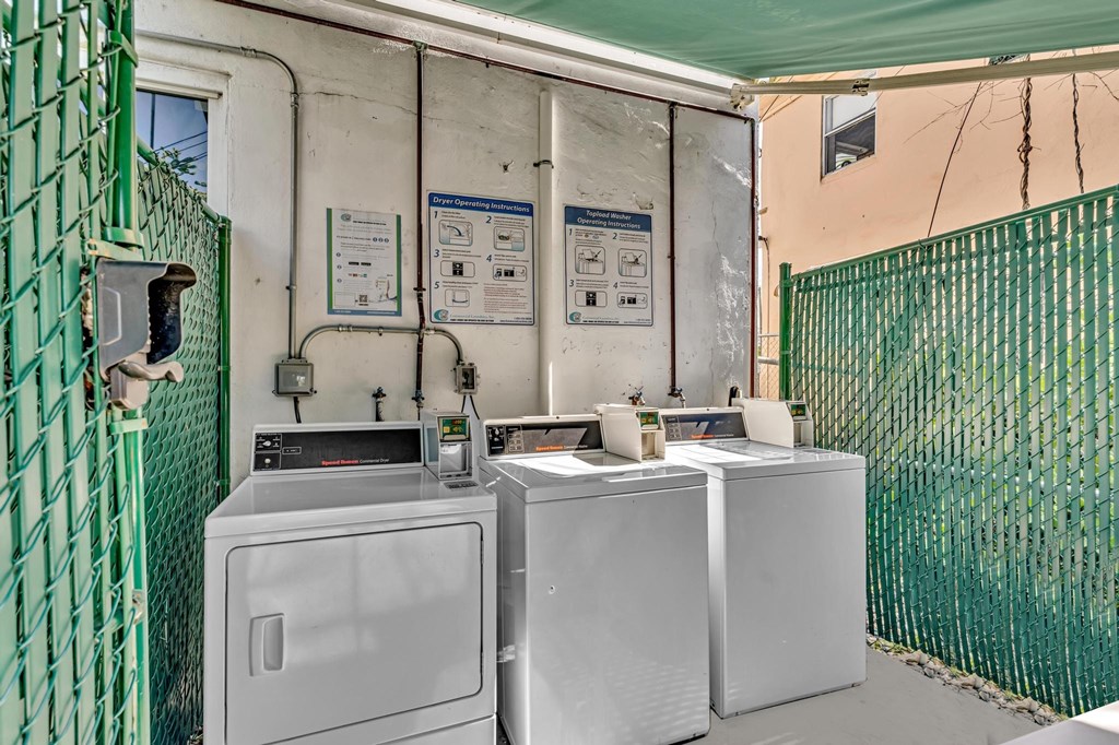A green fence surrounds a washing machine and dryer.