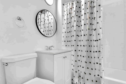 A white bathroom with a tub, sink, and shower curtain.