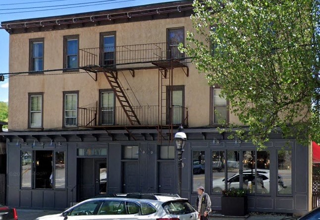 a building with a balcony and cars parked in front of it