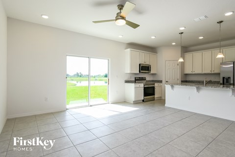 A spacious kitchen and living room with a sliding glass door leading to a green outdoor area.