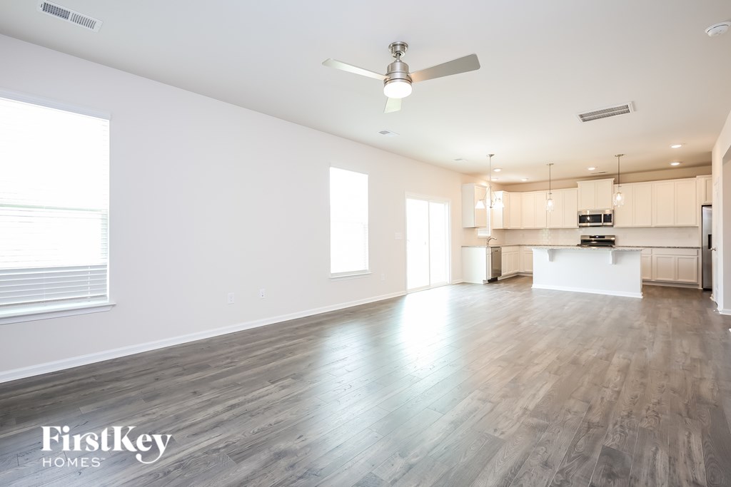 A spacious room with wooden flooring and a ceiling fan.