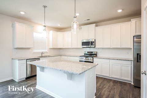 a kitchen with white cabinets and a marble counter top