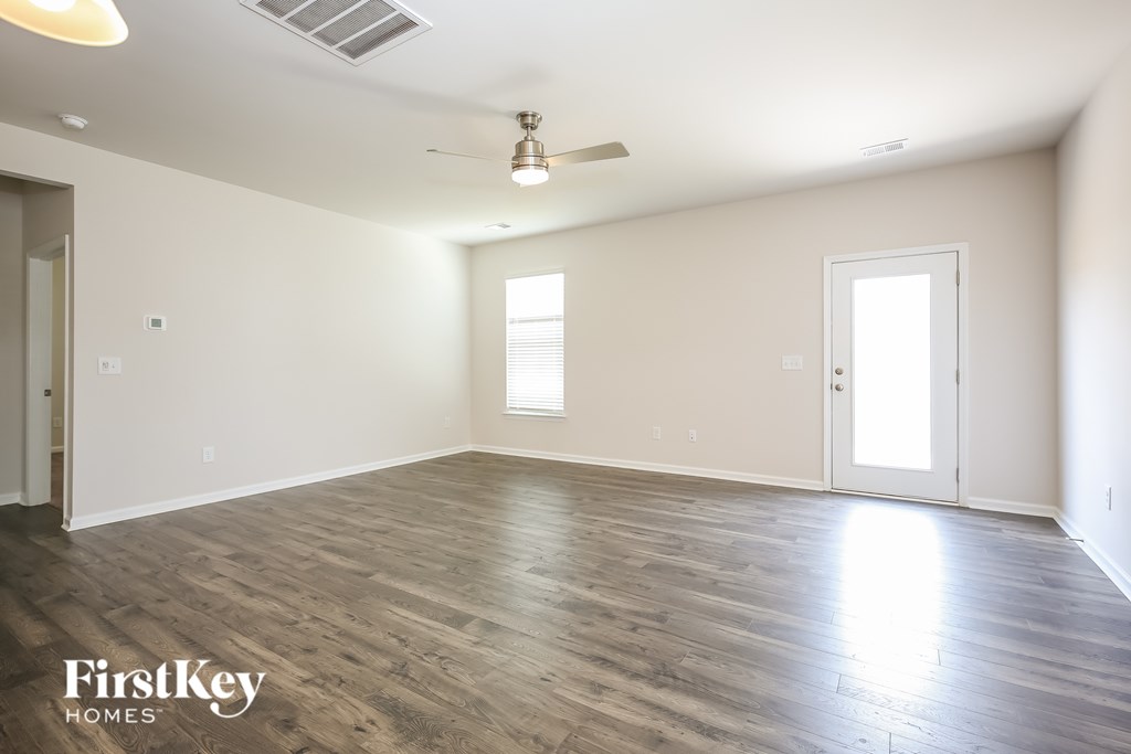 A spacious room with wooden flooring and a ceiling fan.