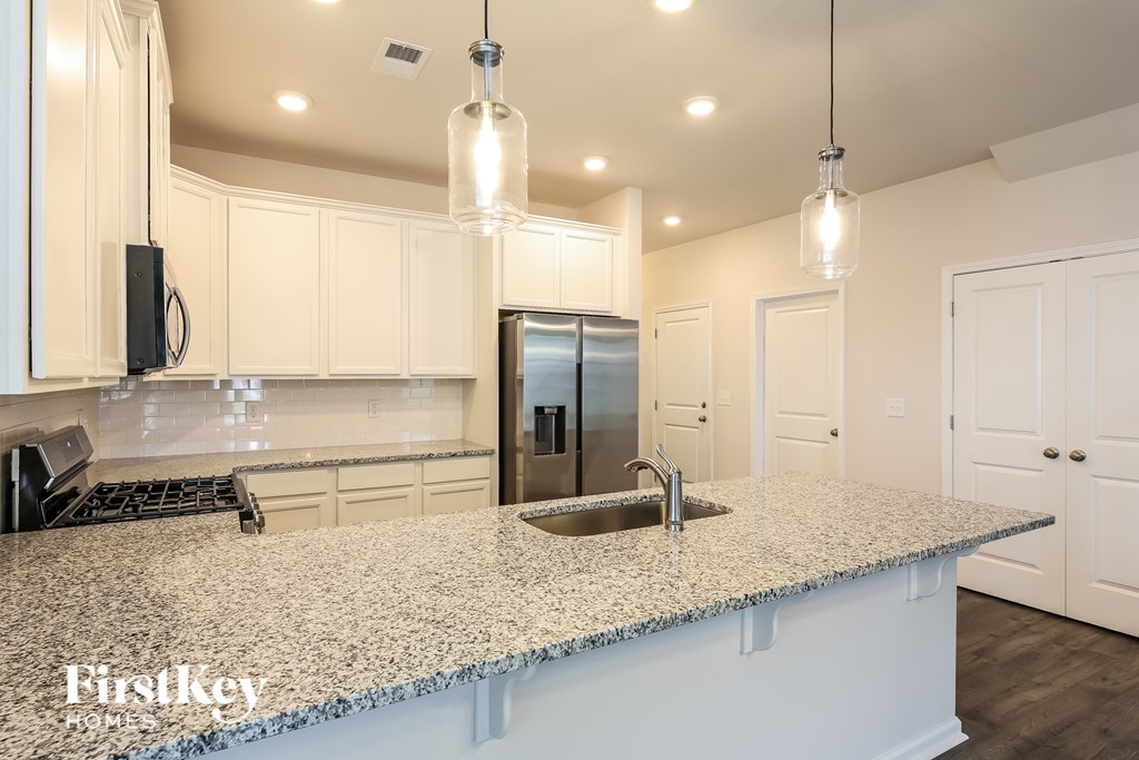A kitchen with a granite countertop and a stainless steel refrigerator.