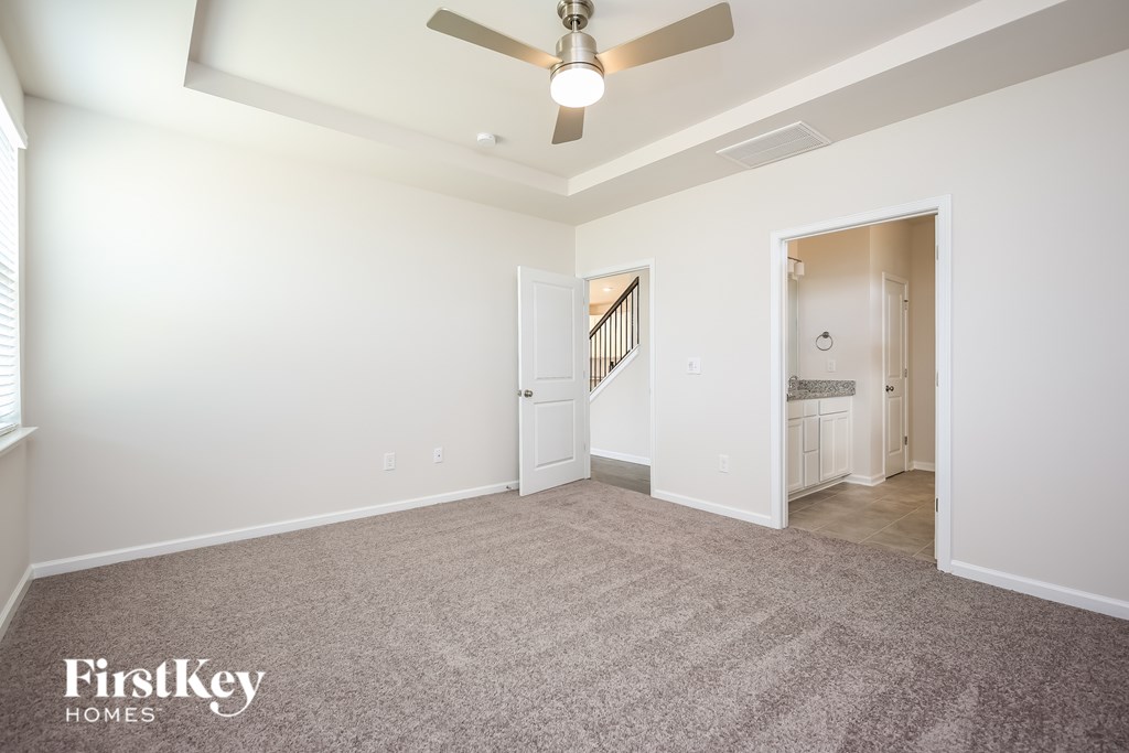 A spacious room with a carpeted floor and a ceiling fan.