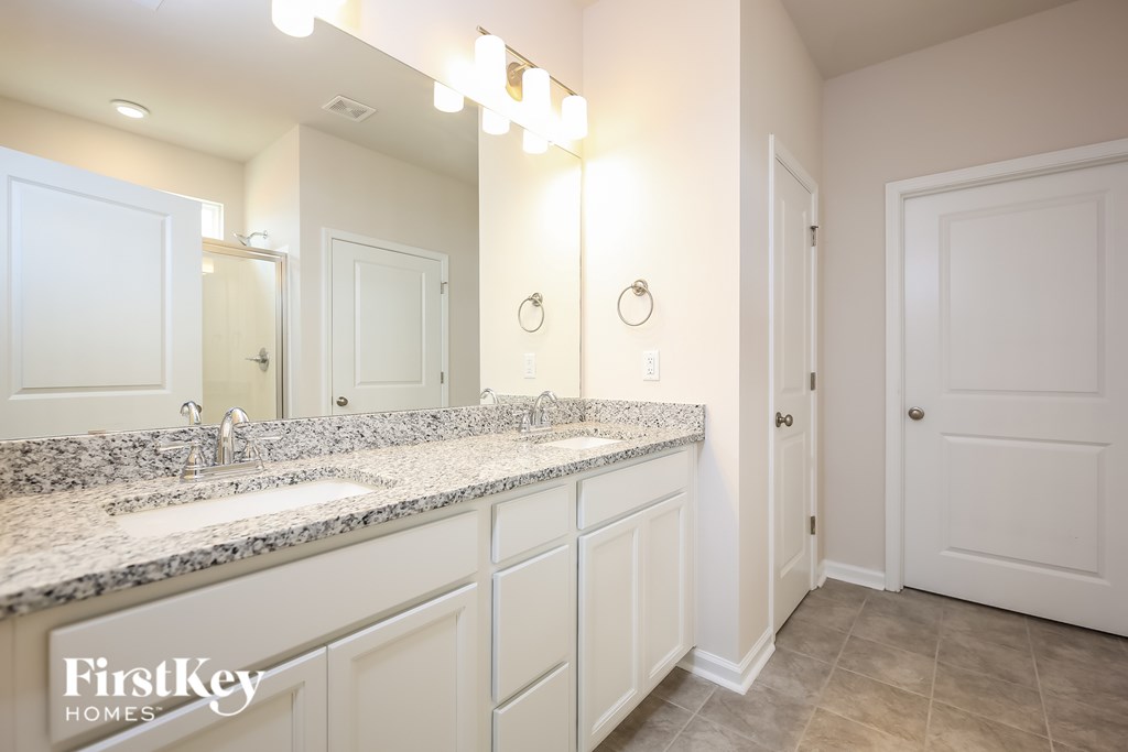 A bathroom with a granite countertop and a large mirror.