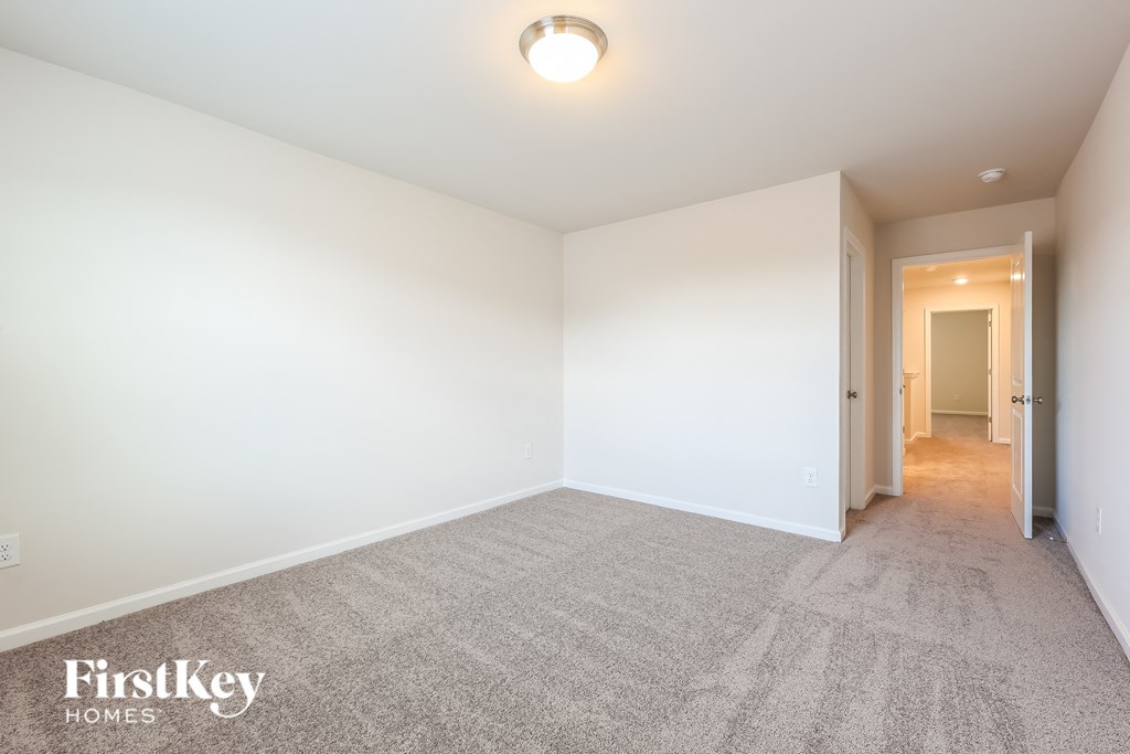 A carpeted room with a light on the ceiling and a doorway leading to another room.