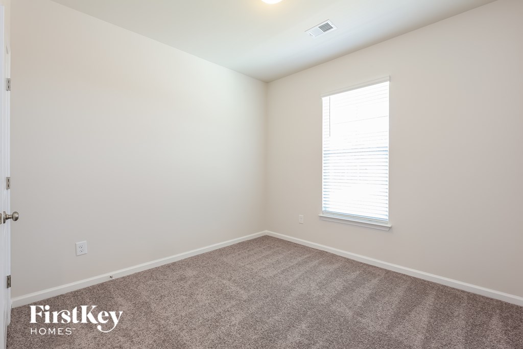 A room with a carpeted floor and a window with blinds.