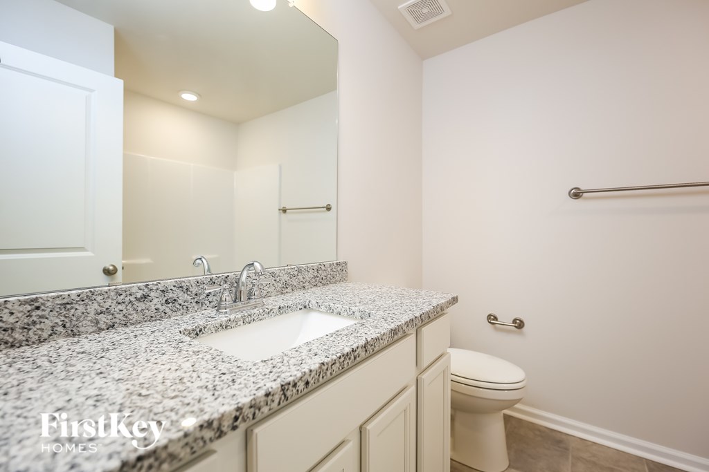 A bathroom with a granite countertop and white fixtures.