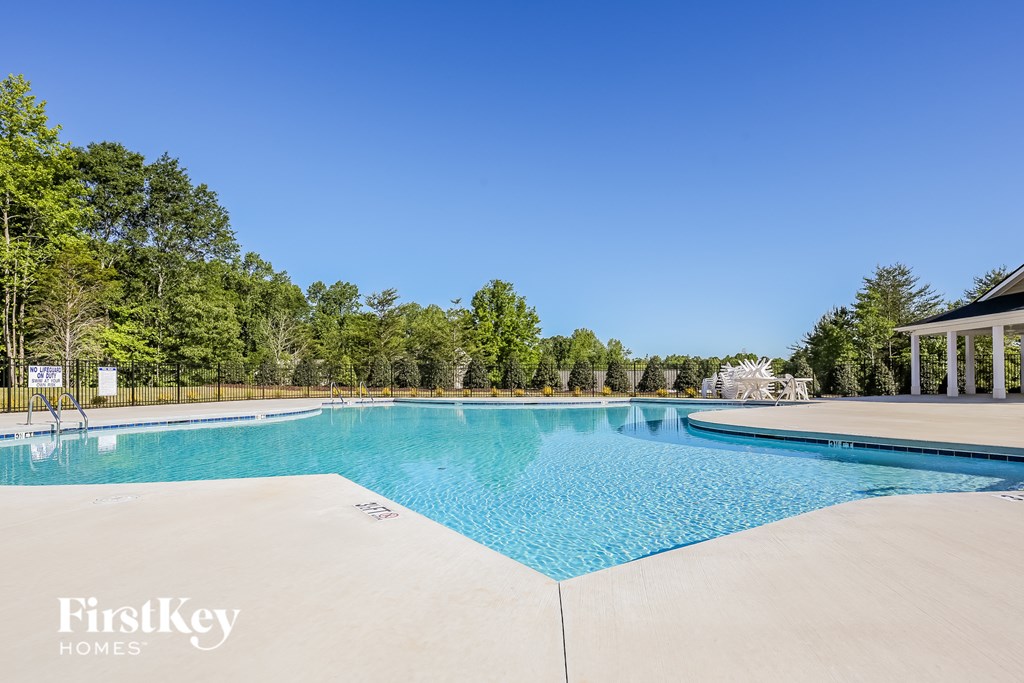 A swimming pool surrounded by trees and a building in the background.