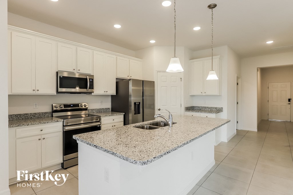 a large kitchen with white cabinets and granite counter tops