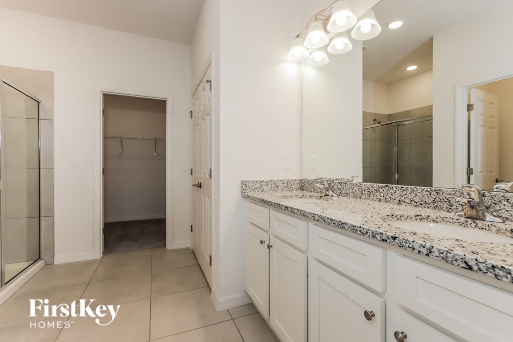 a bathroom with white cabinets and granite counter tops and a shower