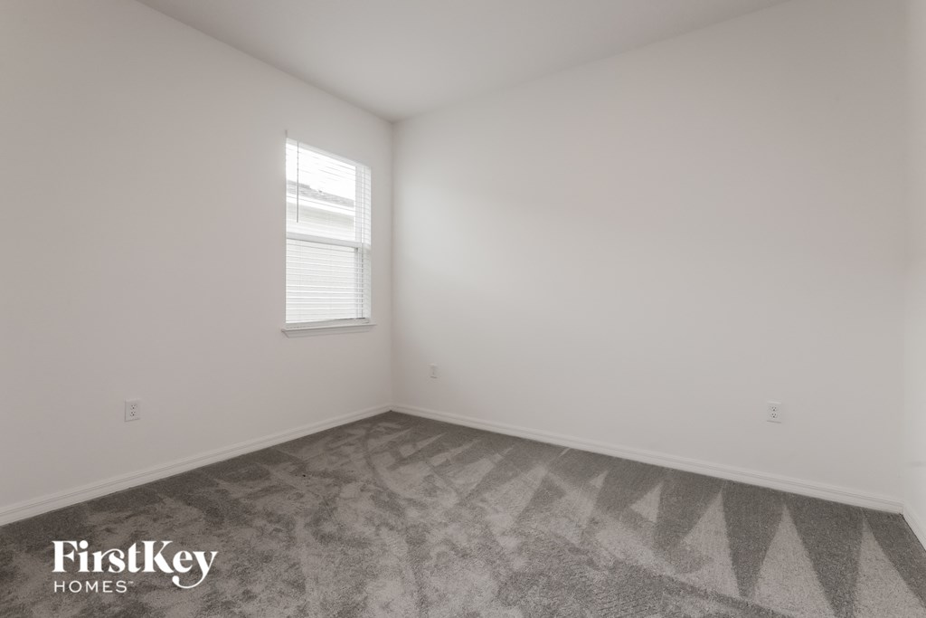 the living room of a home with white walls and a window
