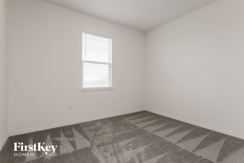 the living room of a home with white walls and a window
