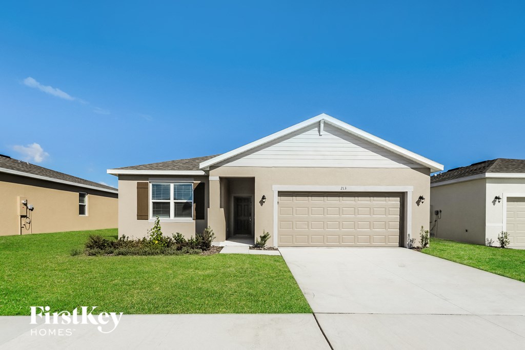a beige house with a garage door and a lawn