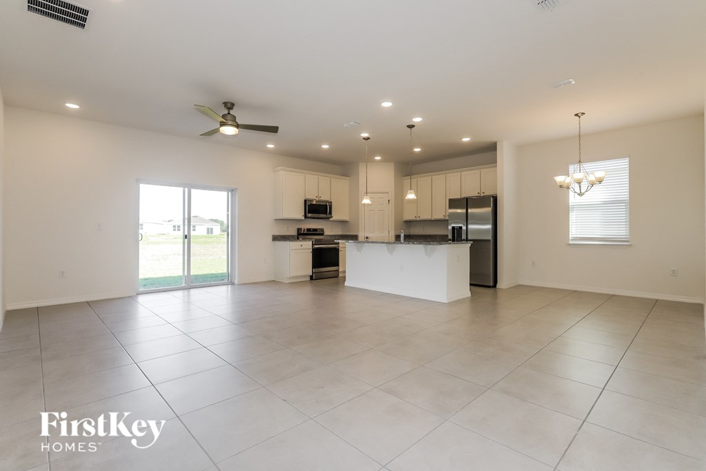 an open kitchen and living room with white tile flooring