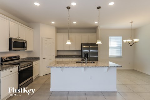 a kitchen with a large island with granite counter tops and white cabinets