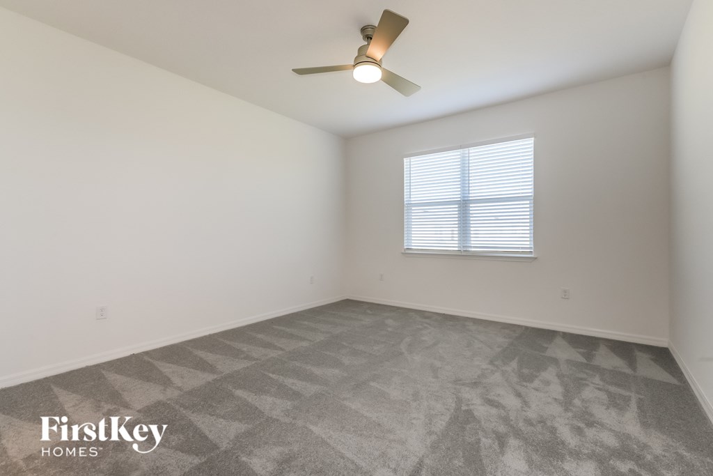 a bedroom with white walls and a ceiling fan and a window