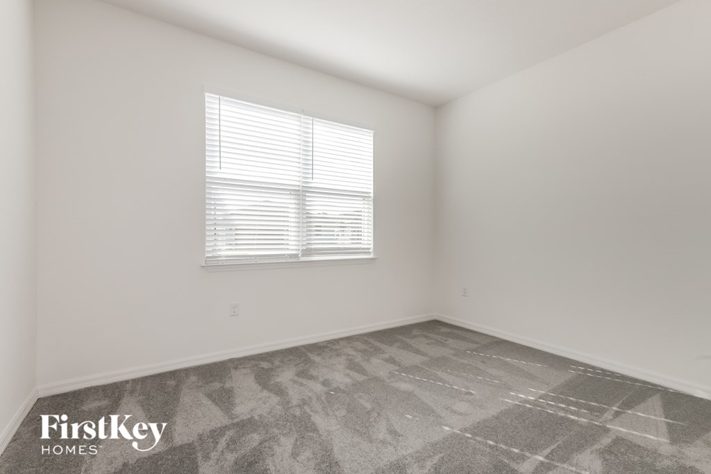 the living room of a home with white walls and a window