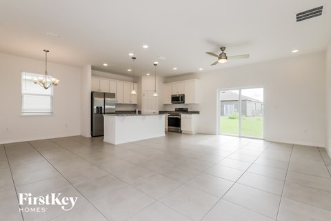 A spacious kitchen and living room with white tiled floors and a ceiling fan.