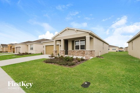 a beige house with a lawn and a sidewalk