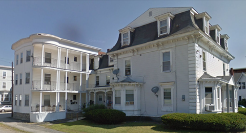 a large white house with a black roof on a street