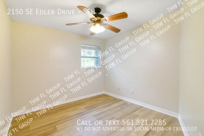 an empty room with white walls and a ceiling fan