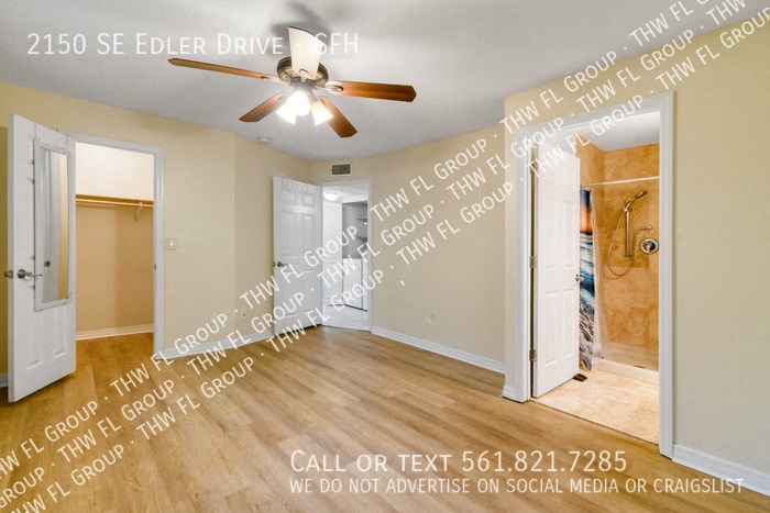 an empty living room with a ceiling fan and an open door to a bathroom