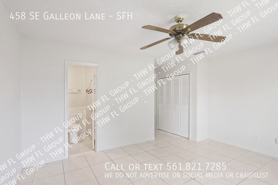 an empty living room with a ceiling fan and a door to a closet