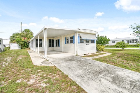 the front of a white house with a concrete driveway