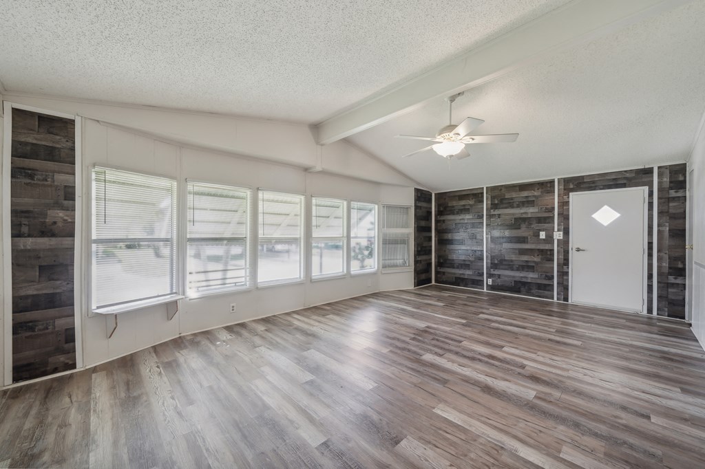 an empty living room with wood flooring and a ceiling fan
