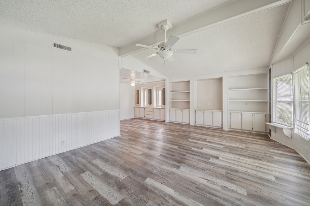 an empty living room with wood floors and a ceiling fan