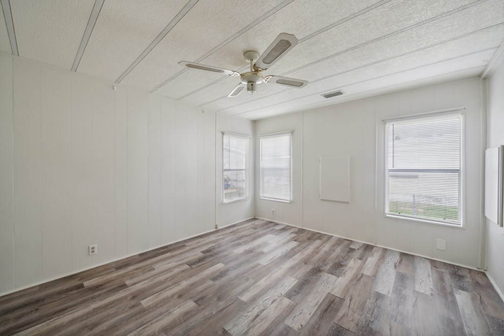 an empty living room with wood floors and a ceiling fan