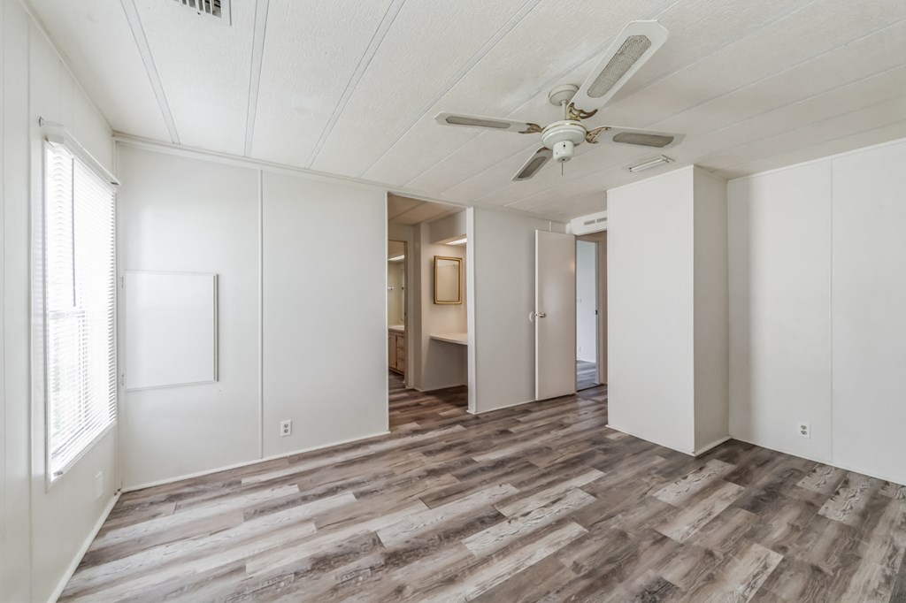 an empty living room with white walls and a ceiling fan