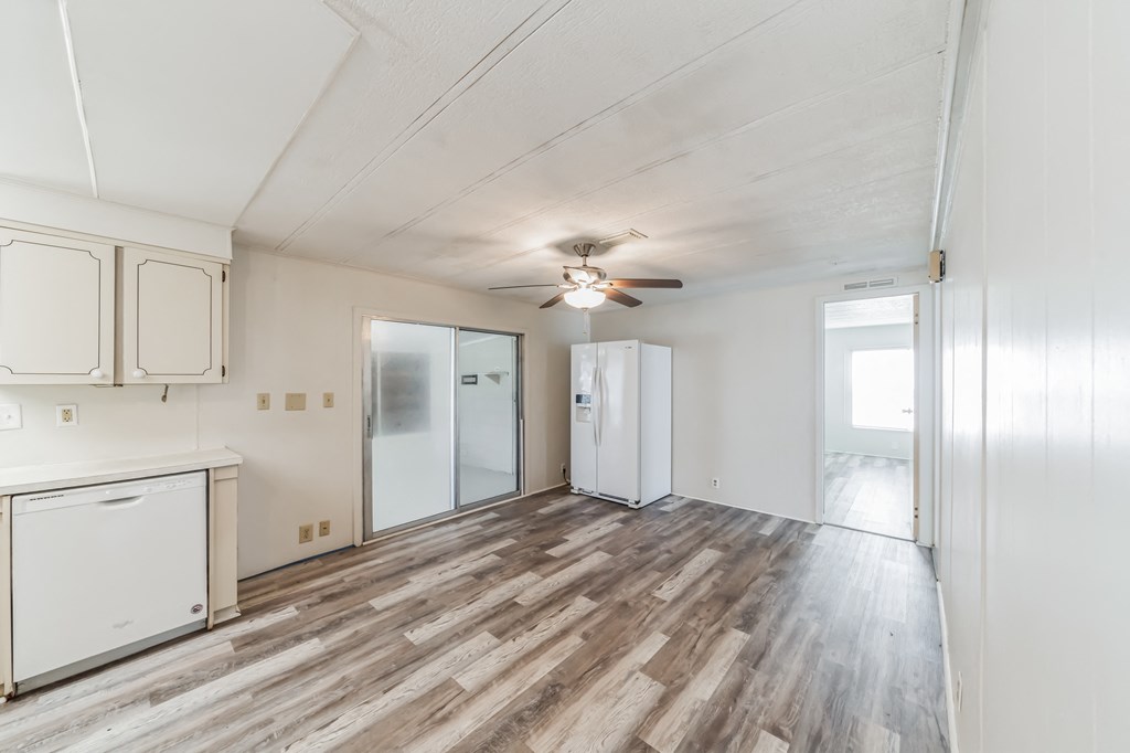the living room of an apartment with a kitchen and a ceiling fan