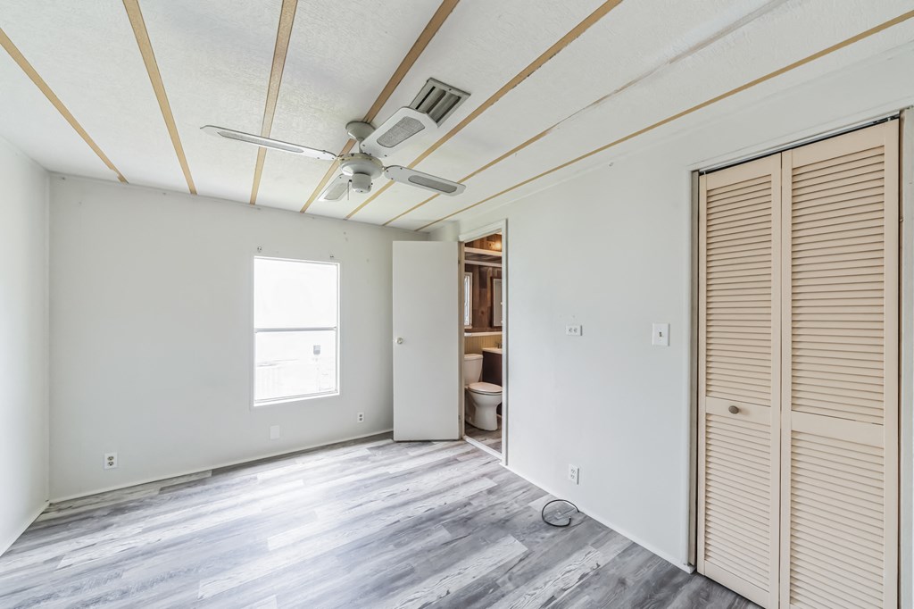 the living room of an empty house with white walls and a ceiling fan