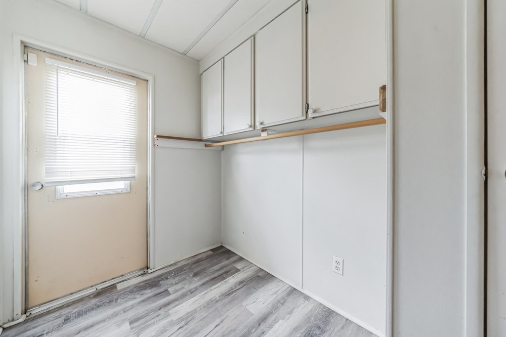 an empty room with white cabinets and a window