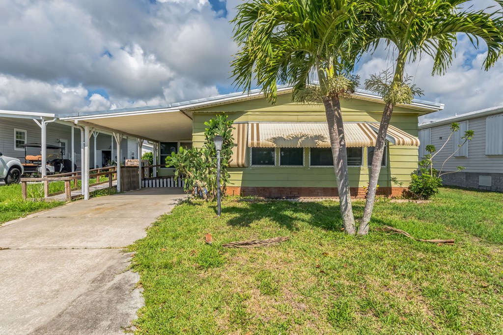 a yellow and green house with palm trees and a driveway