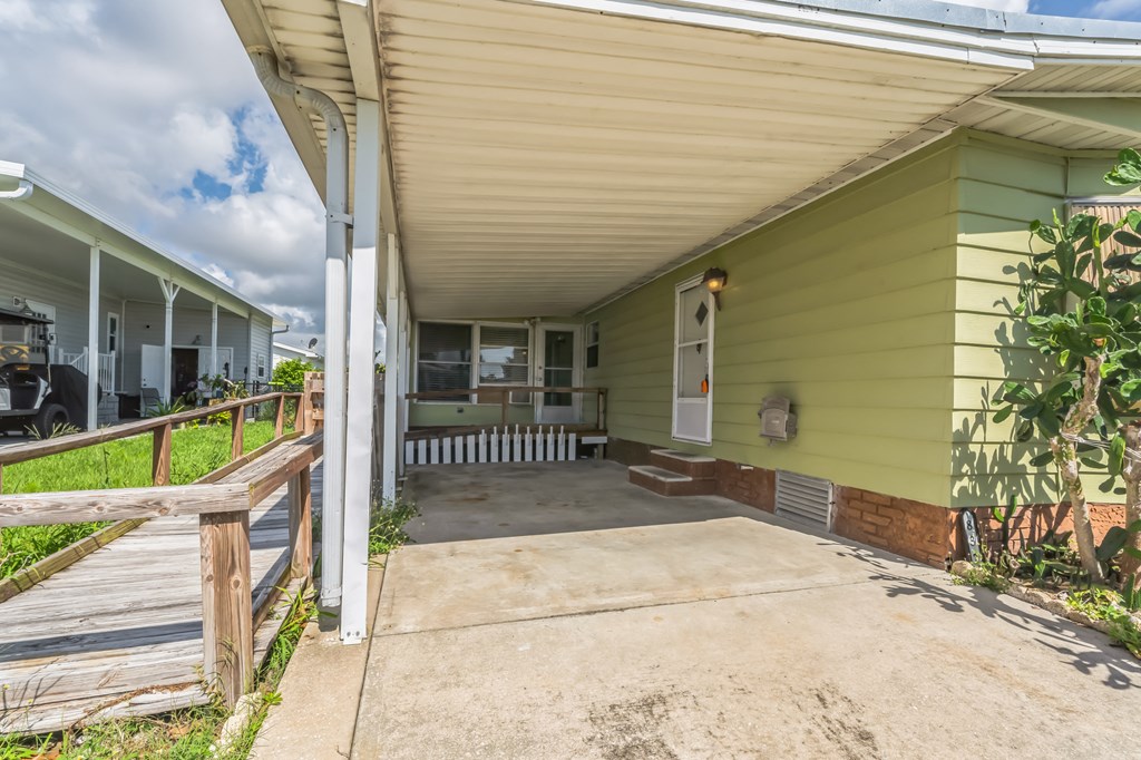 the front porch of a green house with a concrete driveway