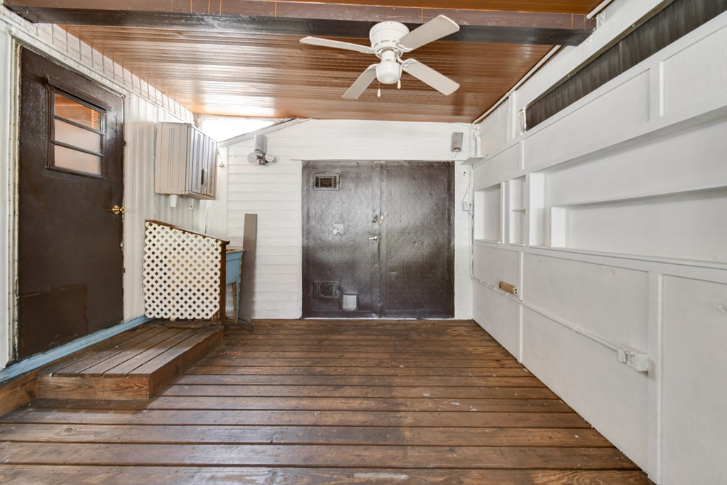 a room with a wooden floor and a ceiling fan and a door