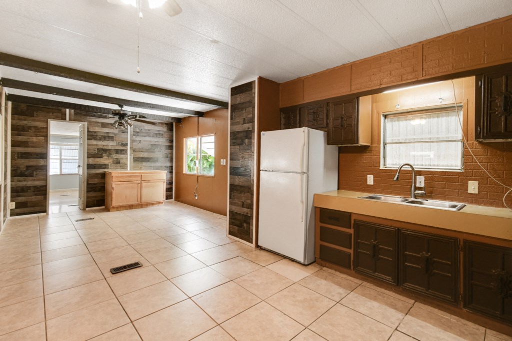 an empty kitchen with a refrigerator and a sink