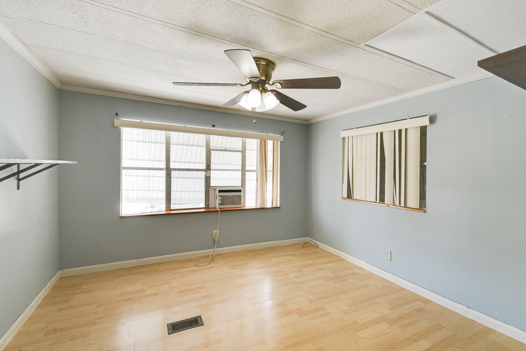 an empty living room with a ceiling fan and a window