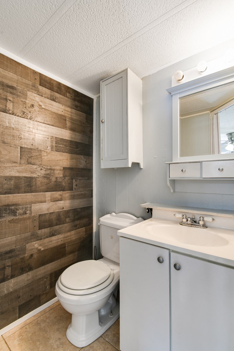 a bathroom with a toilet and a sink and a reclaimed wood wall
