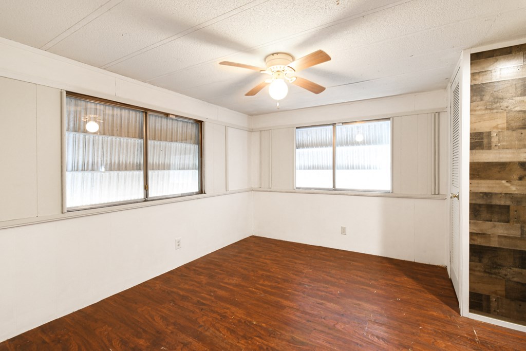an empty living room with wood floors and a ceiling fan