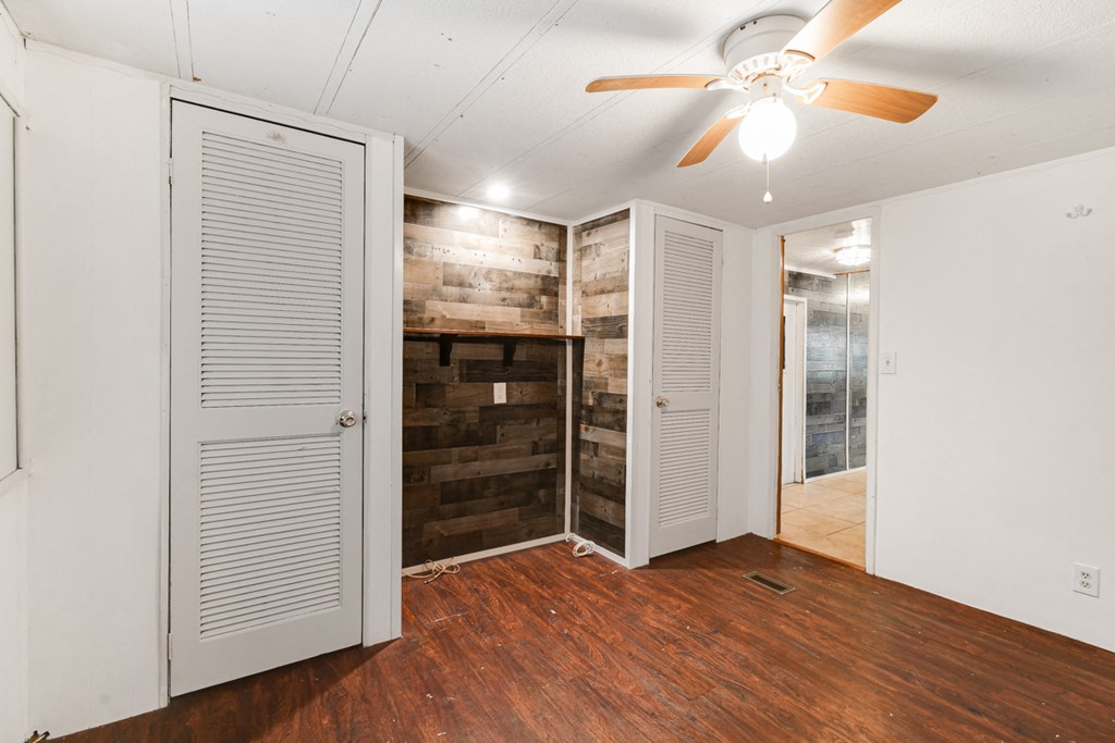 an empty room with a wood wall and a ceiling fan