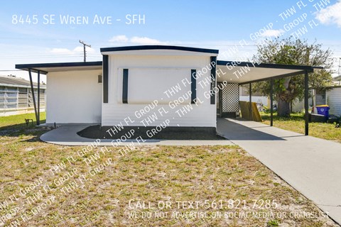 a small white house with a garage and a driveway