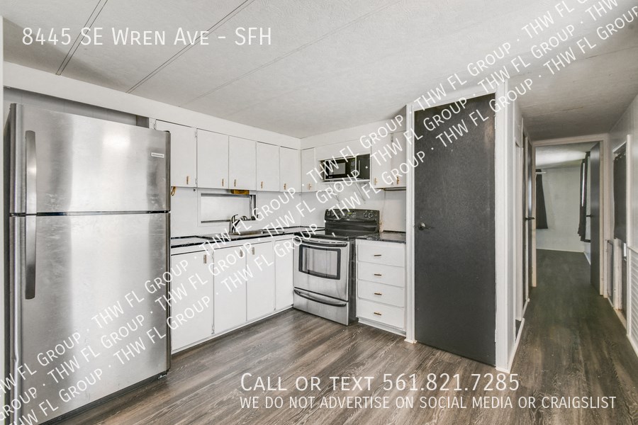 a kitchen with white cabinets and a stainless steel refrigerator